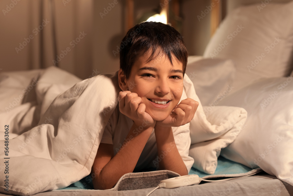 Little boy lying on electric heating pad in bedroom at night Little boy lying on electric heating pad in bedroom at night