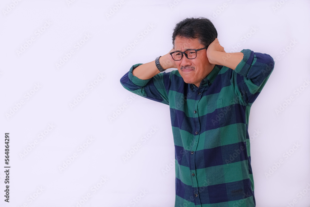 Man standing and blocking his ears with both hands from very loud noise Man standing and blocking his ears with both hands from very loud noise