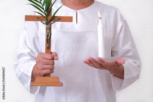 Closeup shot of woman wearing white holding cross and candle on Easter photo