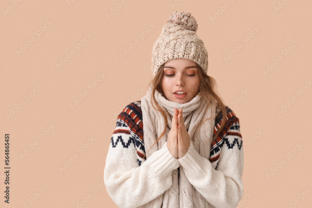 Frozen young woman in winter clothes on beige background Frozen young woman in winter clothes on beige background
