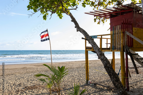 Costa Rica flag on bamboo flagpole on beach colorful lifeguard stand  photo