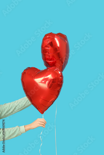 Woman with heart-shaped balloons for Valentine's Day on blue background