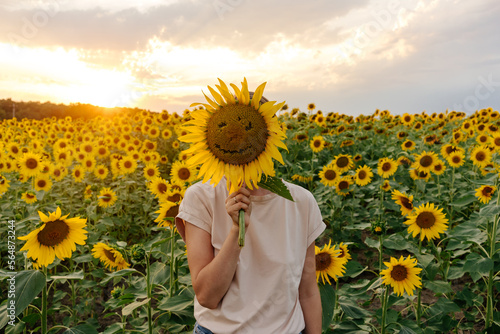 Person covering face with sunflower photo