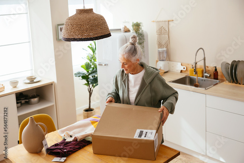 Mature woman unpacking order in kitchen photo