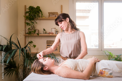 Smiling acupuncture therapist healing young woman