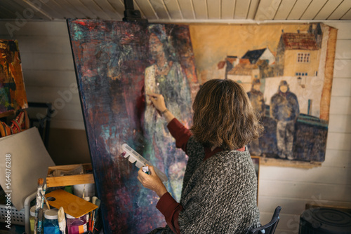 Mature woman artist painting an abstract picture on a canvas