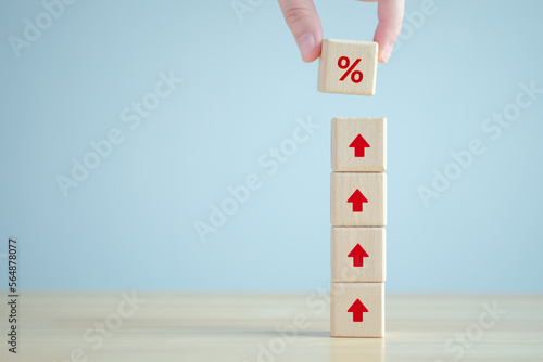 Interest rate finance and mortgage rates. Hand holding percentage sign from rise of arrow up on wooden stack. financial growth, interest rate increase, inflation, sale price and tax rise concept.