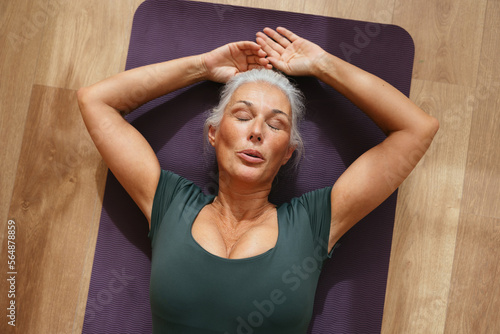 Exhausted woman resting on mat after fitness exercises photo