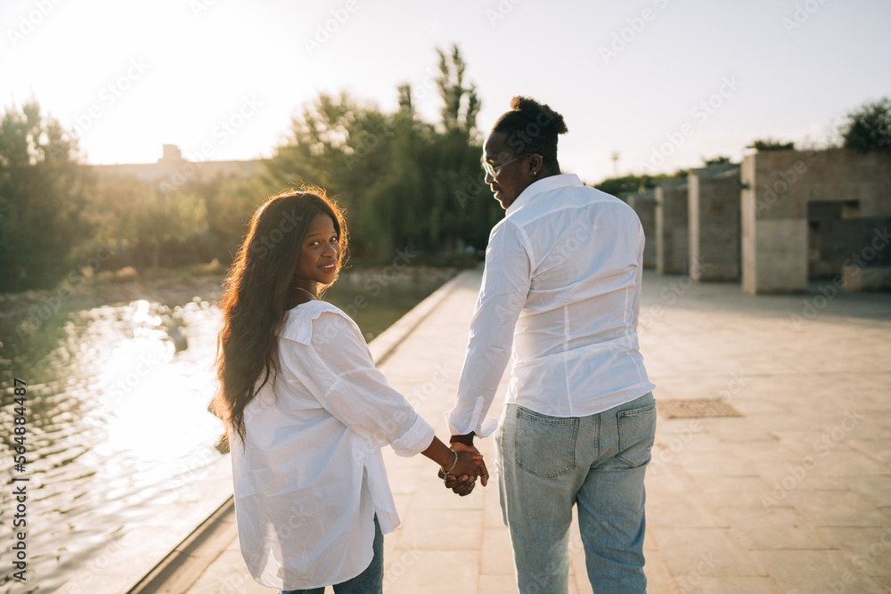 Couple holding hands and walking on embankment