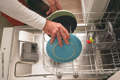 man putting dishes in the dishwasher photo