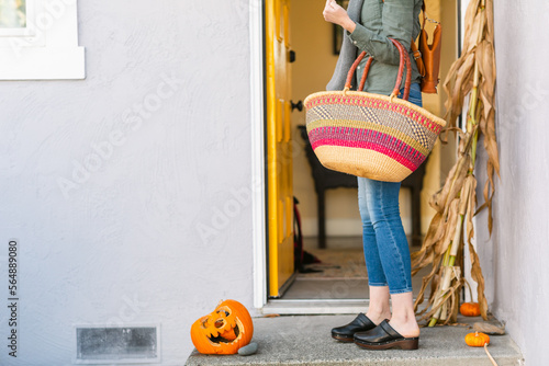 Crop woman leaving home with shopping bag photo