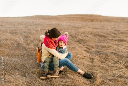 Mother hugs her son sitting on barren ground  photo
