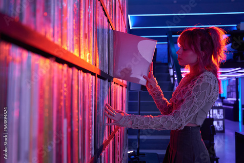 Female meloman putting LP record on shelf photo