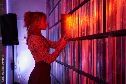Woman choosing vinyl discs from shelf in shop photo