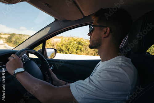 Young man driving a car with the steering wheel on the right hand side