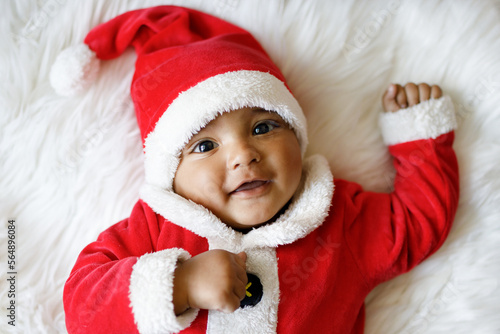Cute baby wearing santa claus costume smiling at camera photo