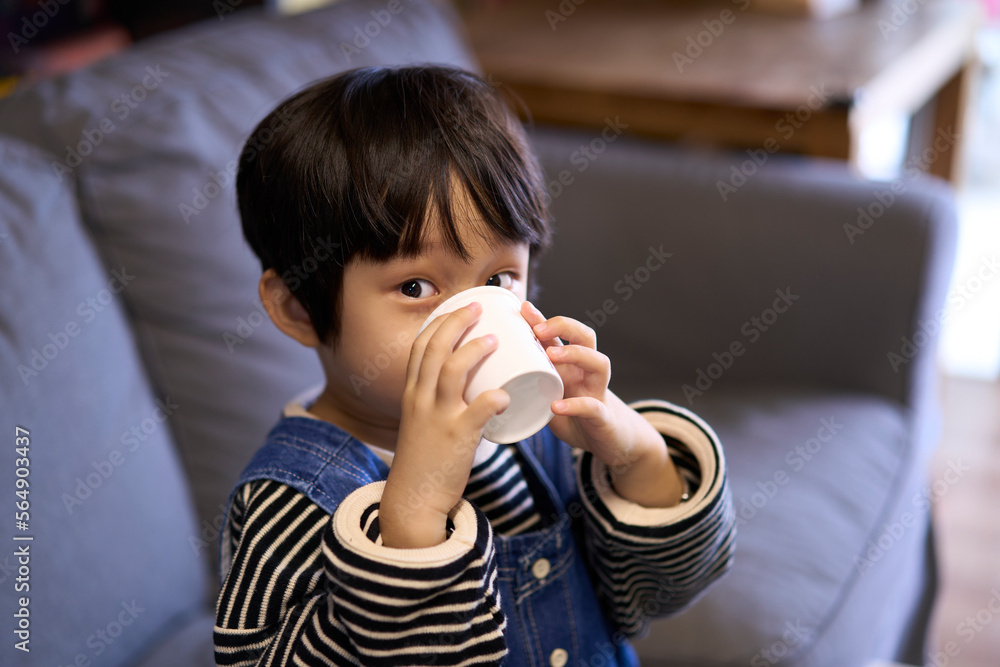 Asian little boy, drinking water on the sofa Asian little boy, drinking water on the sofa