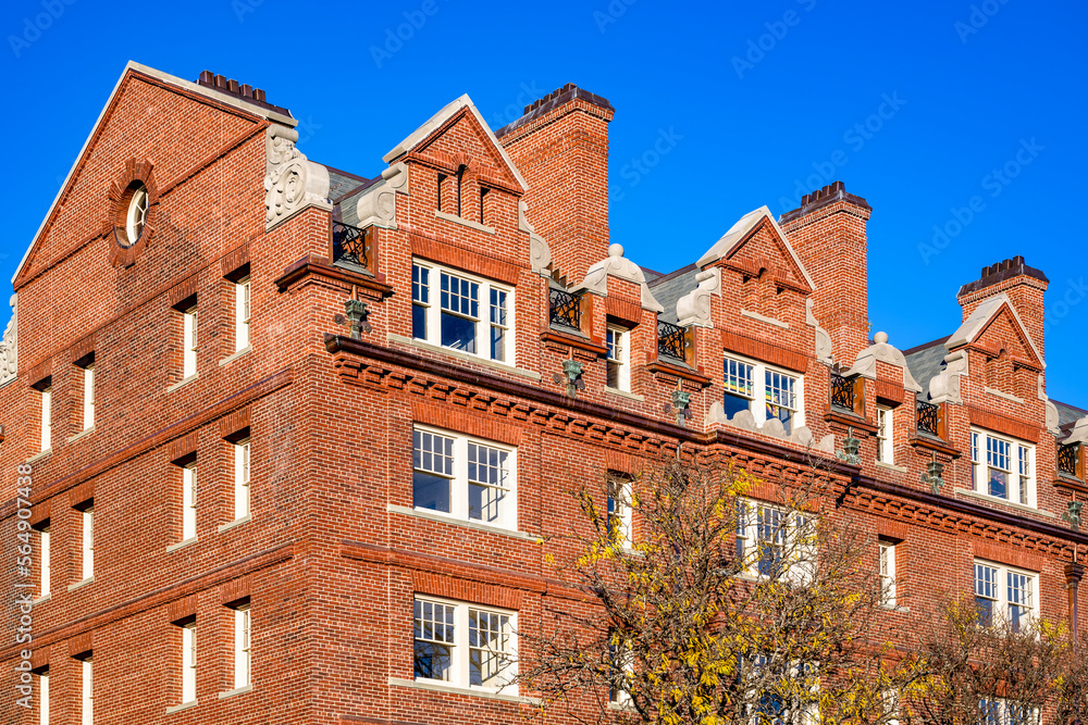 Classic New England red brick high-rise apartment building with loft apartments and fall leafed maple