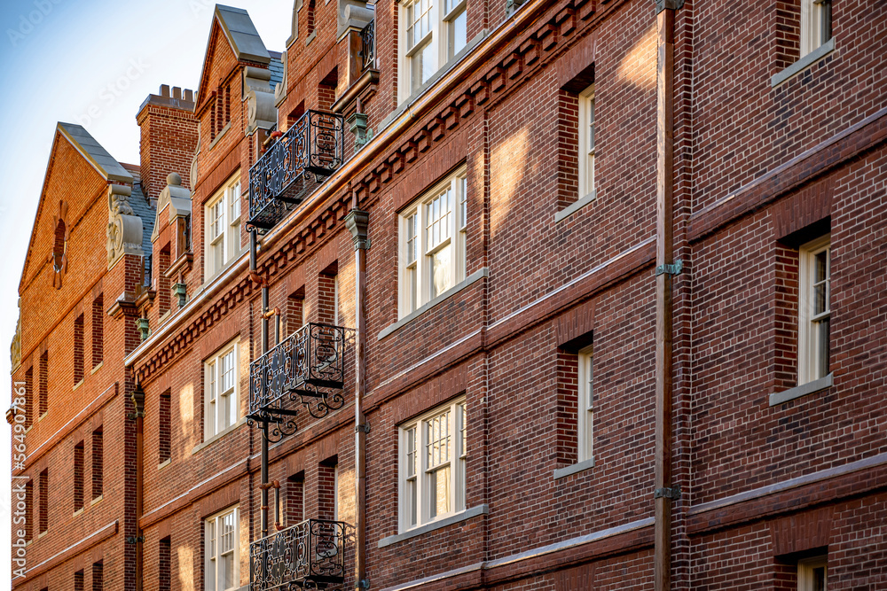 High-rise red brick residential building with attic apartments and carved wrought-iron balconies in New England