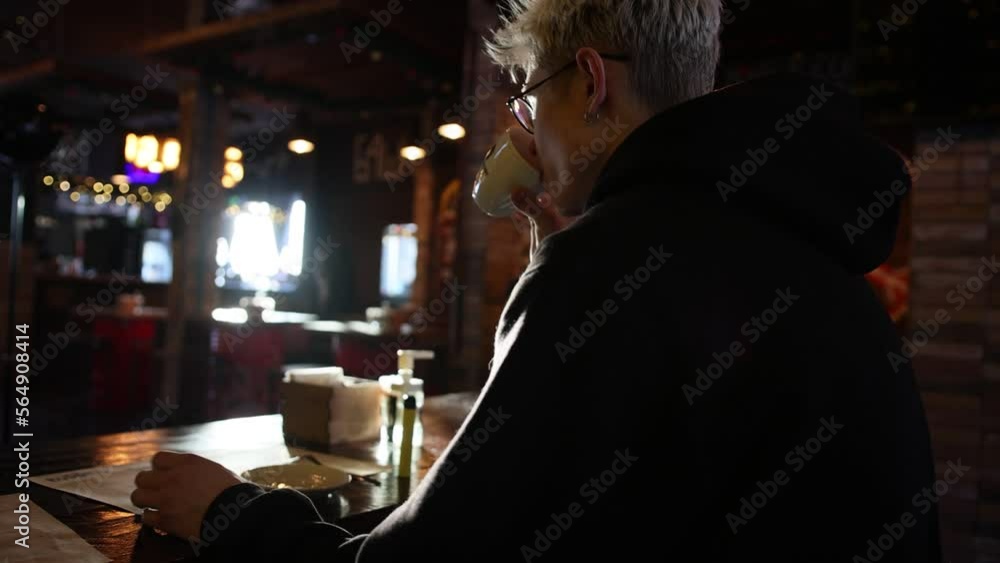 Young handsome man drinks hot coffee cup on a wooden table and uses mobile phone. Hot Coffee Drink Concept. Young handsome man drinks hot coffee cup on a wooden table and uses mobile phone. Hot Coffee Drink Concept.