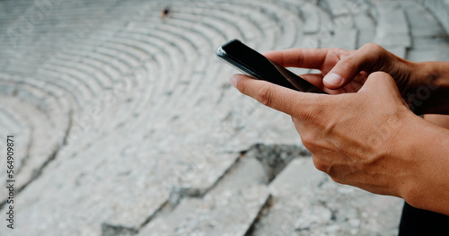 using his phone in the Ancient Theatre of Epidaurus, banner format photo