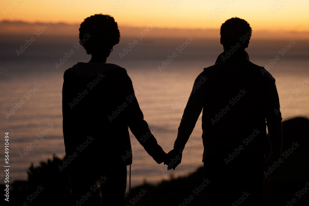 Sunset, beach and silhouette of couple holding hands for date by the sea with dark shadow, love and care. Horizon, ocean and people rear with together in nature for hiking or travel goals on holiday