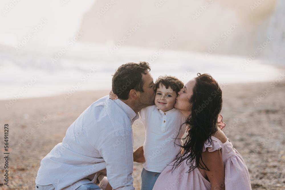 Parents Kiss Their Son Near Ocean in summer Parents Kiss Their Son Near Ocean in summer