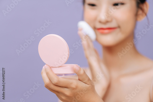Beautiful young asian woman applying powder puff on cheek makeup photo