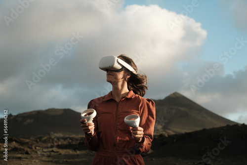 Woman wearing VR glasses and joysticks in Metaverse photo