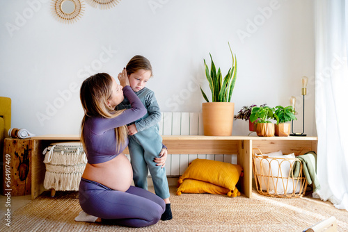 Pregnant mom comforts her angry daughter at home photo