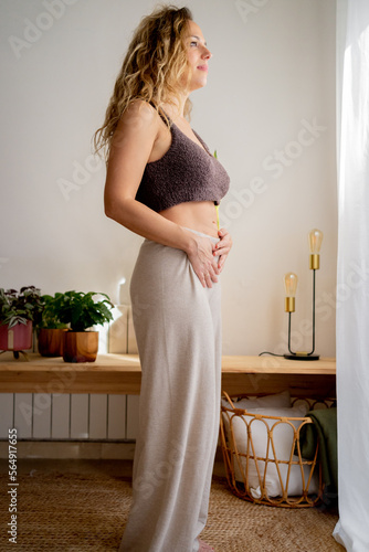 Pensive woman touching her belly at home