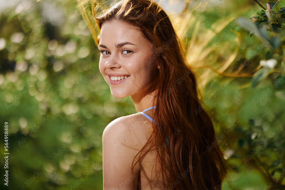 Woman with a beautiful smile with teeth and long hair in the spring sunset in nature in the park near the flowering trees happiness Woman with a beautiful smile with teeth and long hair in the spring sunset in nature in the park near the flowering trees happiness