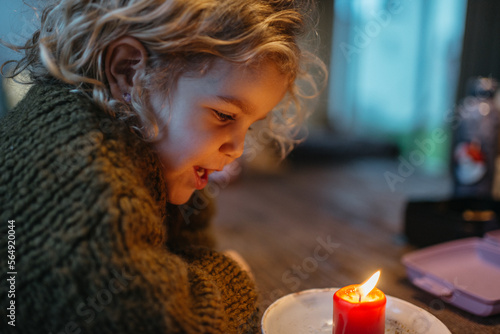 Kid looking at red candle burning