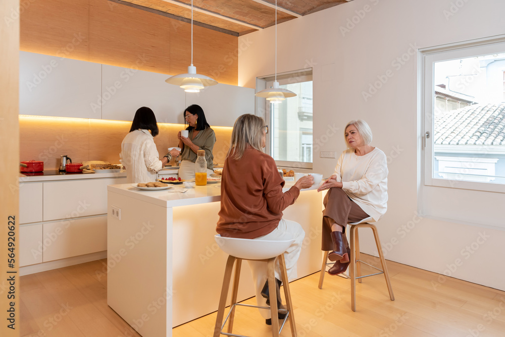 Elegant mature women resting in stylish kitchen Elegant mature women resting in stylish kitchen