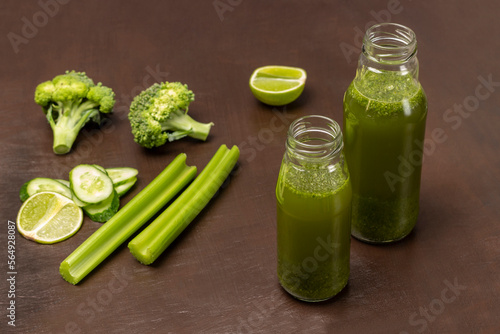 Two smoothie bottles. Celery stalks, broccoli and lime wedges.