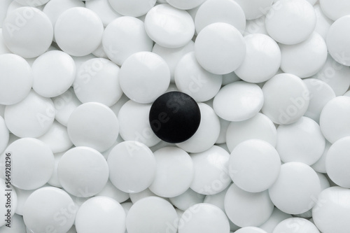 One black Go stones and many white Go stones.