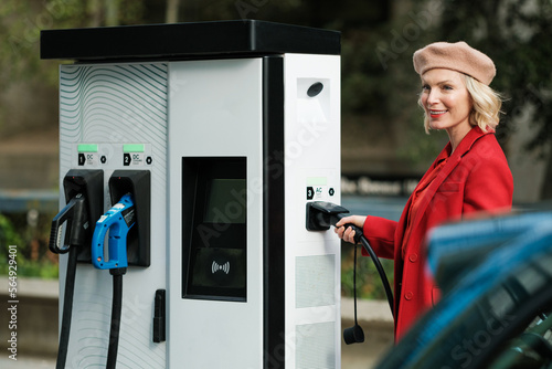 Woman recharging Electric Car on Charge Station photo