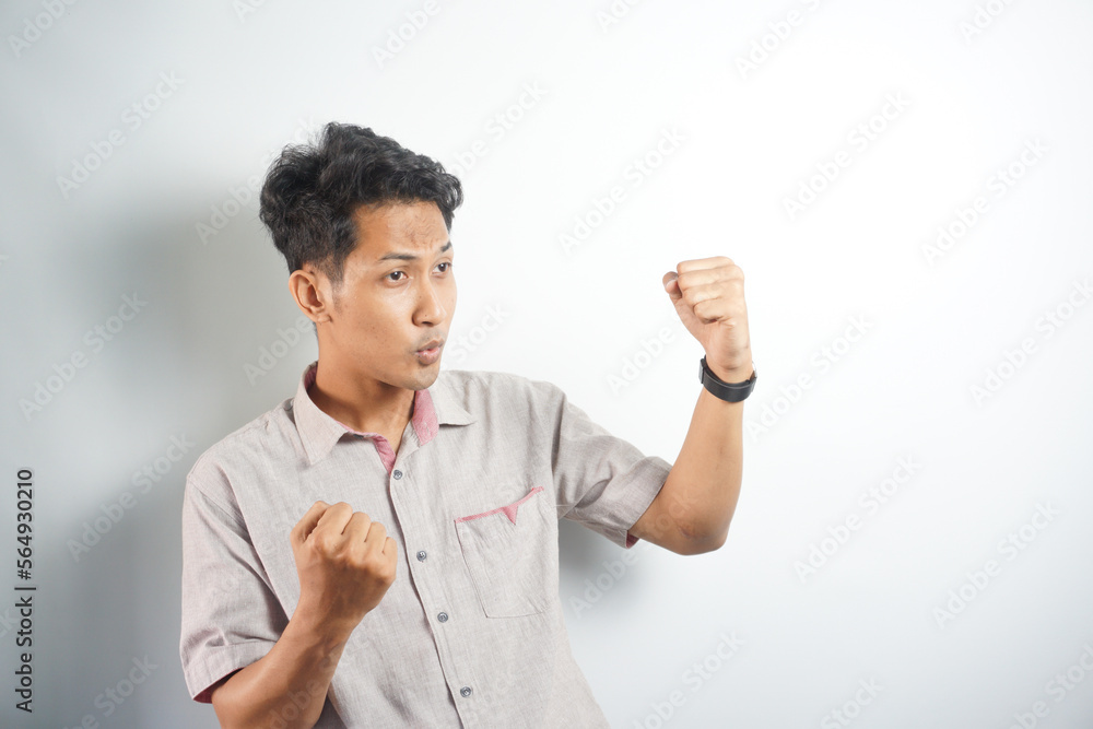 excited Asian man celebrating success with two fists in air isolated on the blue background. close up portrait, studio shot , happiness, positive emotion and feeling. I've done it. facial expression excited Asian man celebrating success with two fists in air isolated on the blue background. close up portrait, studio shot , happiness, positive emotion and feeling. I've done it. facial expression
