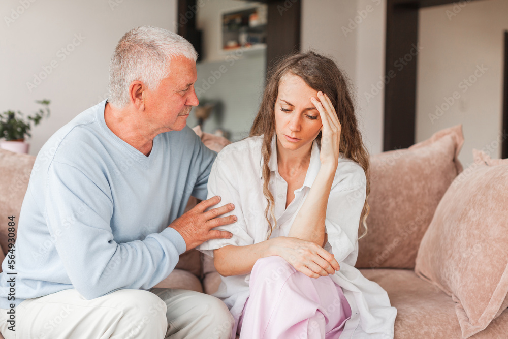 Worried aged father embracing comforting sad grown up daughter with broken heart family sit on sofa Worried aged father embracing comforting sad grown up daughter with broken heart family sit on sofa