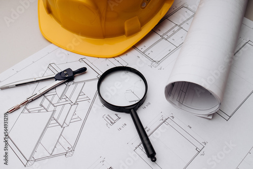 Blueprint and yellow safety helmet on workplace desk