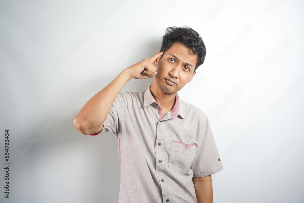Handsome asian young man wearing shirt standing on white background confused and wondering about question. Uncertain with doubt, thinking. dream concept Handsome asian young man wearing shirt standing on white background confused and wondering about question. Uncertain with doubt, thinking. dream concept