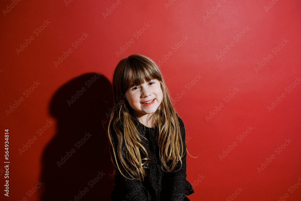 classic flashy portrait of smiling toddler girl in front of red wall classic flashy portrait of smiling toddler girl in front of red wall