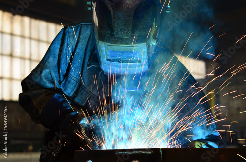 Workers wearing industrial uniforms and Welded Iron Mask at Steel welding plants, industrial safety first	
