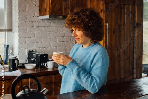 Beautiful Young Woman Drinking Tea in Her Kitchen photo