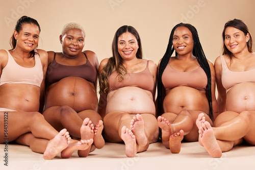 Pregnant, body or portrait of women sitting on studio background floor in relax support, mothers day or diversity. Happy smile, pregnancy or bonding friends in underwear for stomach growth or health