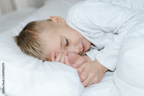 Мальчик спит в кровати . белая постель