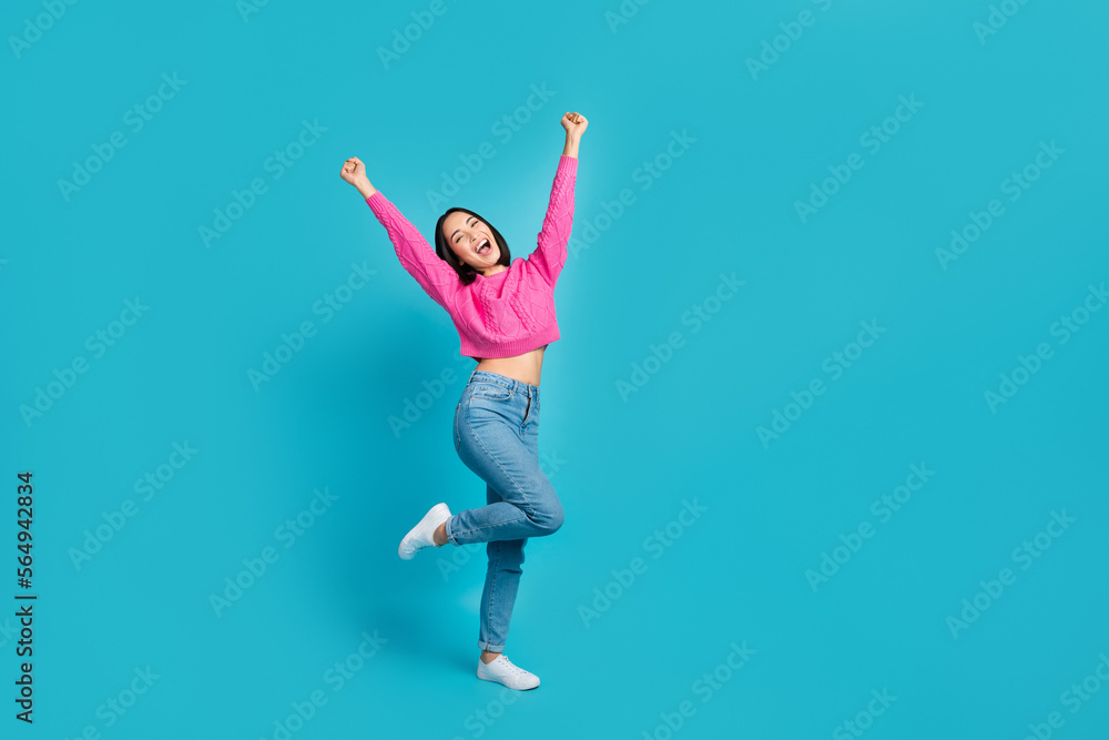 Full body portrait of ecstatic positive indonesian lady raise fists success empty space isolated on blue color background