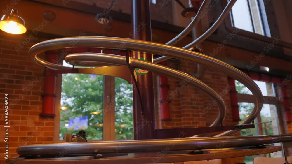 On metal track from top to bottom moves a pot with a cooked dish in a modern restaurant attraction. Process of delivery of ready-made food in pots directly from the kitchen from the second floor On metal track from top to bottom moves a pot with a cooked dish in a modern restaurant attraction. Process of delivery of ready-made food in pots directly from the kitchen from the second floor