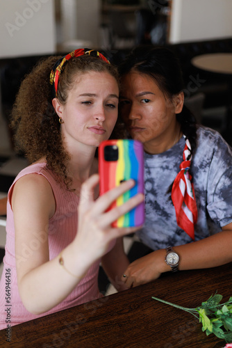 Girlfriends. Pretty multiracial female friends taking selfie with smartphone Lifestyle selfie portrait of two young positive woman taking a self photo.