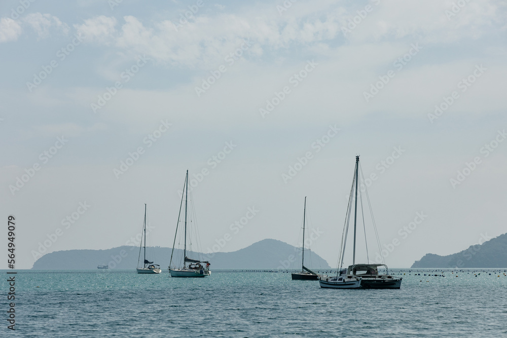 yachts are moored near the sea against the backdrop of mountains in the haze